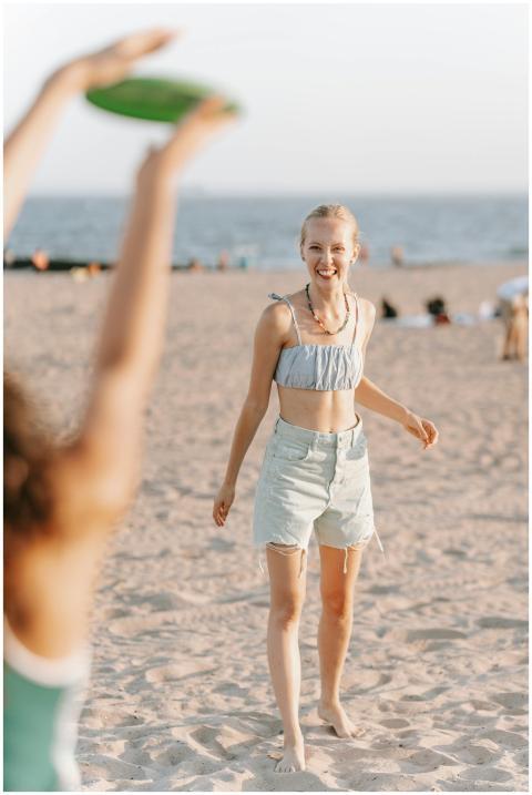 Two young women playing frisbee on a sunny beach,