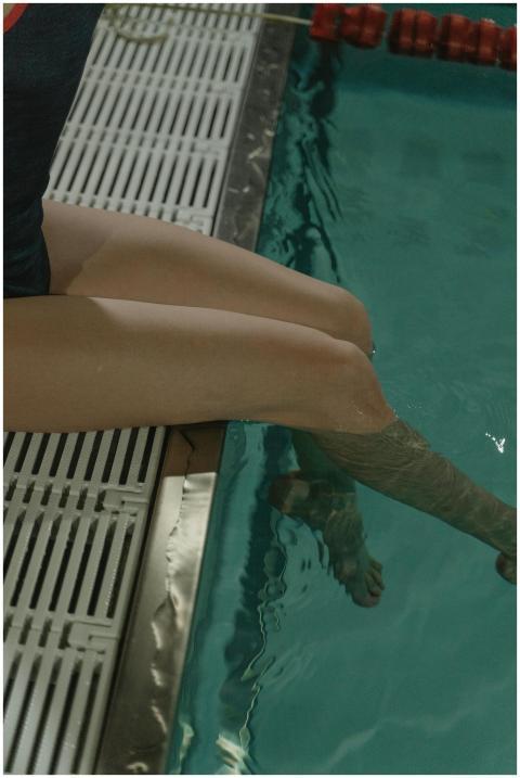 Close-up of a person dipping their legs into a swi