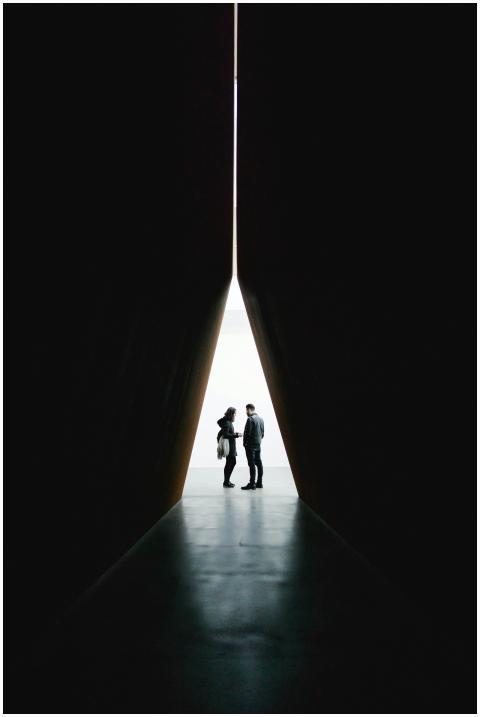 Silhouette of two people standing in a dramatic tu