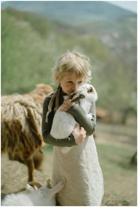 Young girl holding a rabbit in a serene countrysid