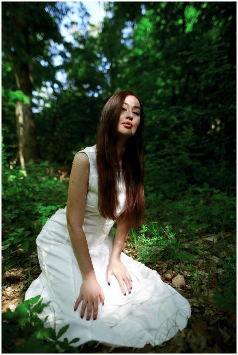 A model with long brown hair in a white dress knee