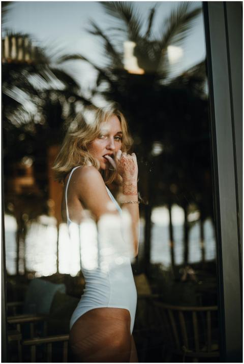 Blonde woman in a white swimsuit posing behind a g