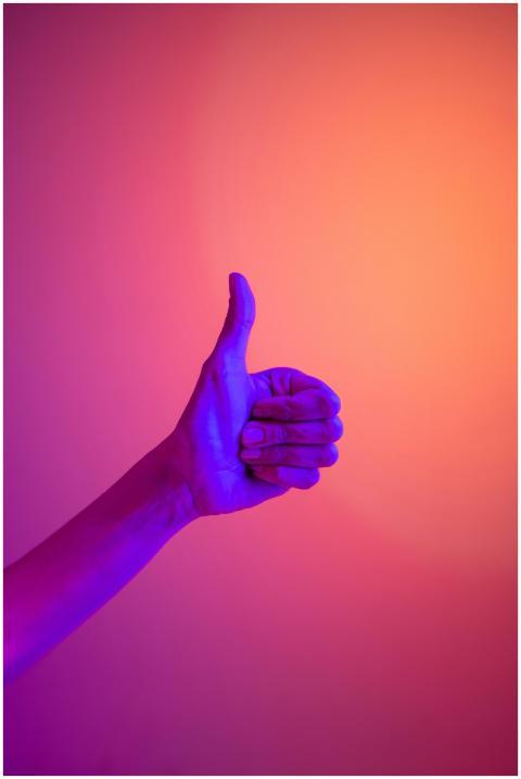 A neon-illuminated hand giving a thumbs up against
