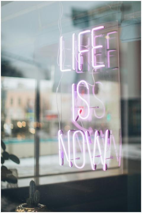 Urban scene with a glowing 'Life is Now' neon sign