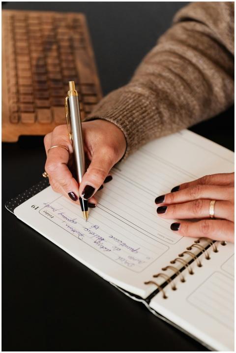 Close-up of a woman's hands writing in a planner o