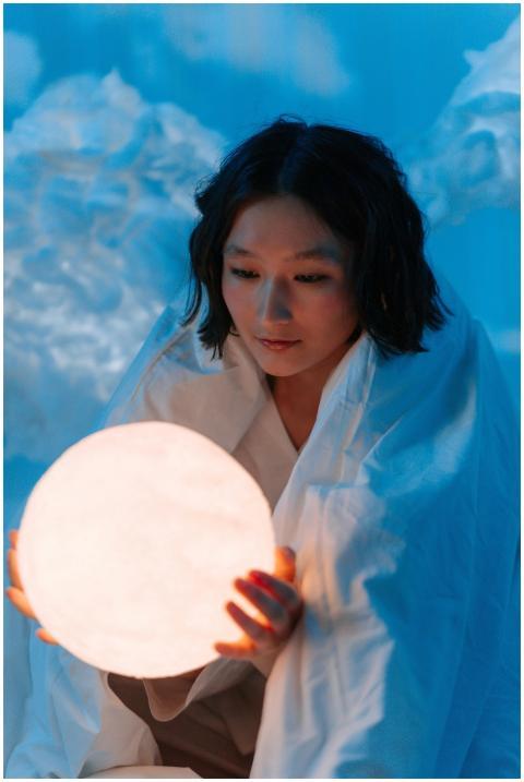 Asian woman wrapped in a blanket holding a glowing
