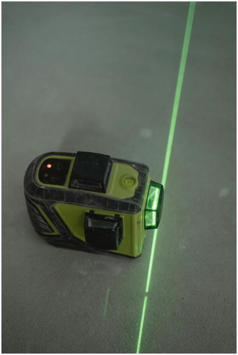 A green laser level projecting a line on a concret