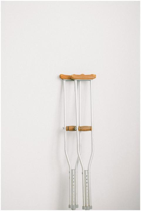 Minimalist image of crutches leaning on a white wa