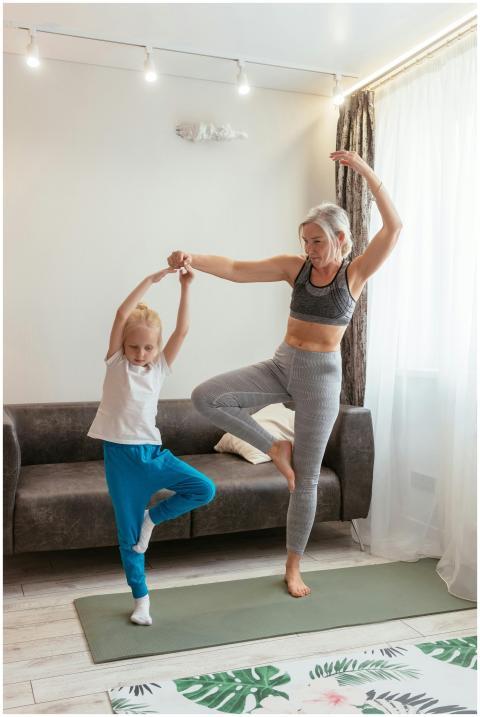 A senior woman and young girl enjoy yoga in a cozy