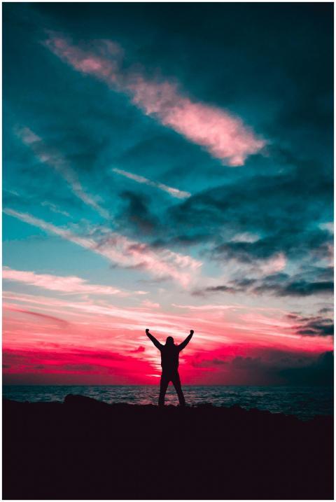 Person silhouetted against a vibrant sunset sky ov