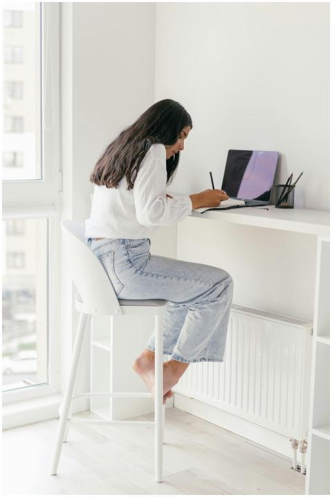 A young woman sits at a desk, focusing on her lapt