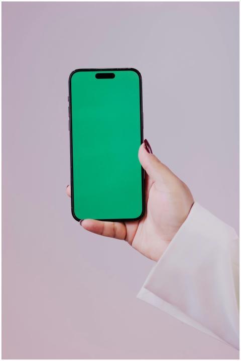 Close-up of a hand holding a smartphone with a gre