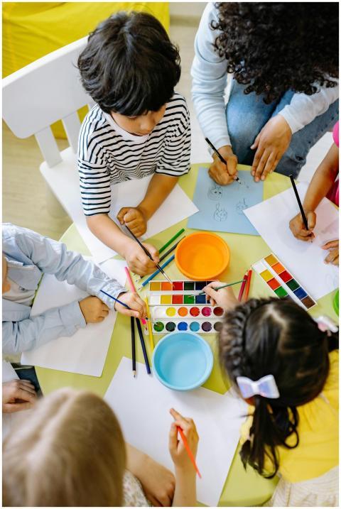 Top view of children painting with watercolors at