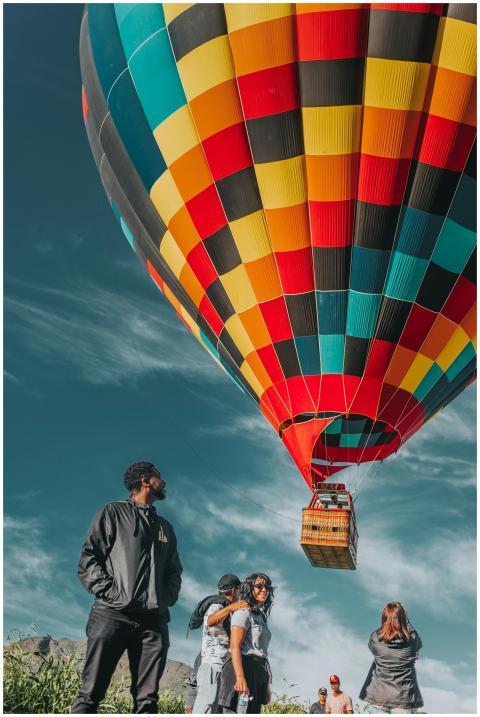 A colorful hot air balloon soars above a group enj