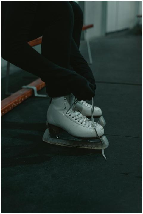 Close-up of a person tying ice skates on a bench i