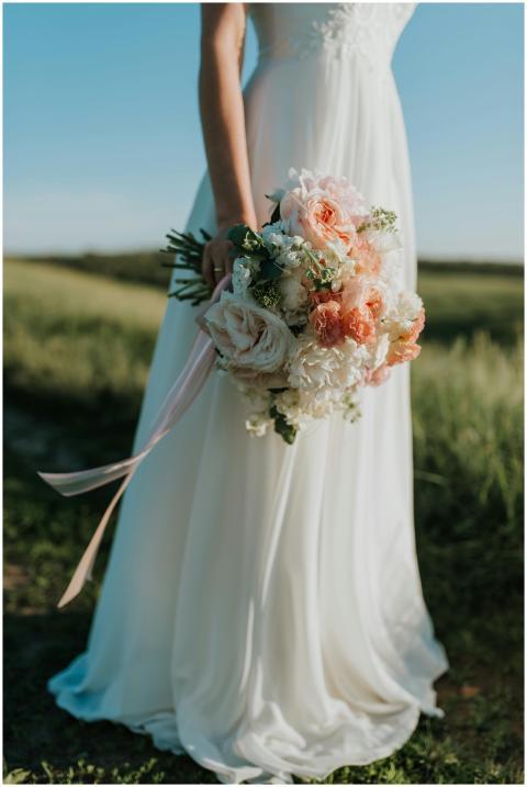 A bride in a flowing white gown holds a colorful b