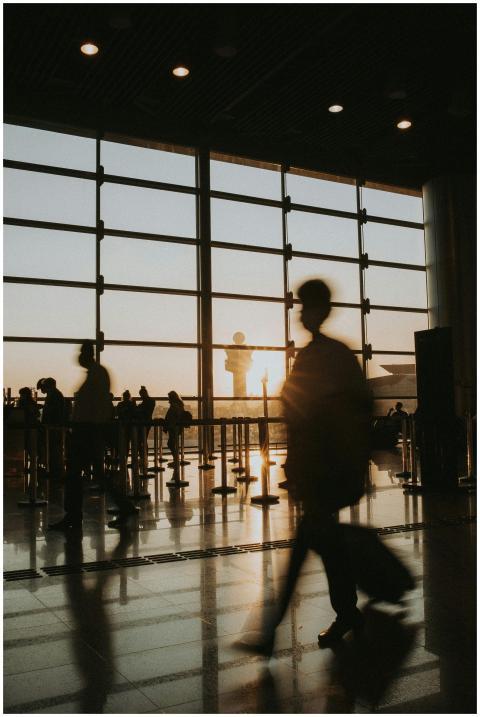 Passengers silhouetted against sunrise in an airpo