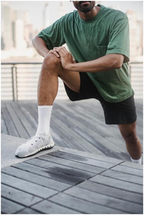 Adult man in green t-shirt stretching on a wooden