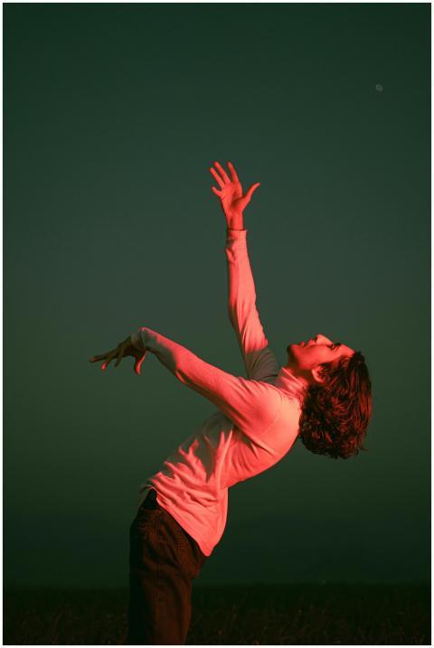 Young man with arms raised in dramatic pose under