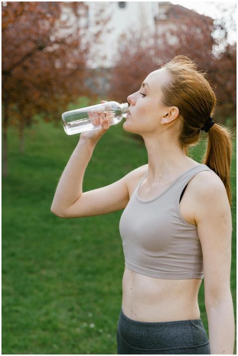 Fit woman in activewear drinking water outdoors, p