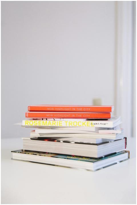 A neatly stacked pile of hardcover books on a whit