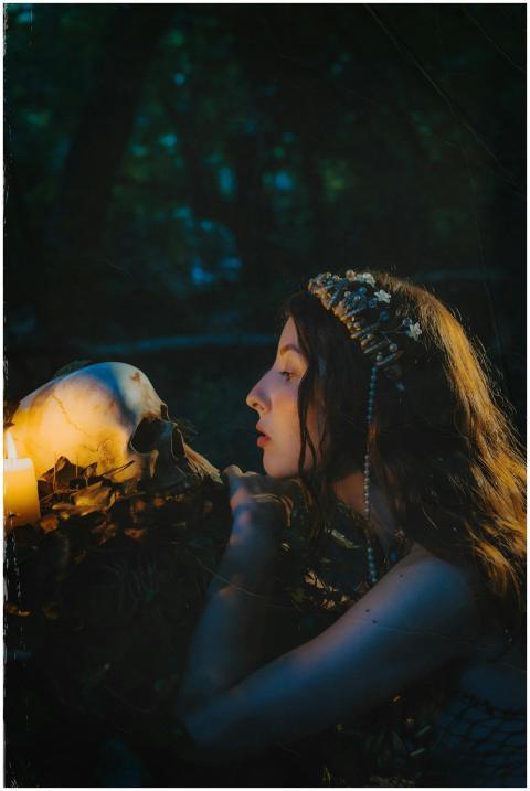 A mysterious woman with a wreath gazes at a skull