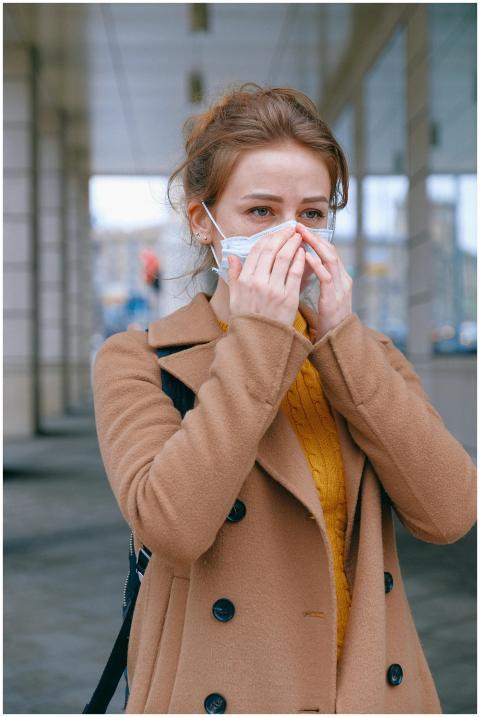 Woman in coat wearing a mask outdoors, symbolizing