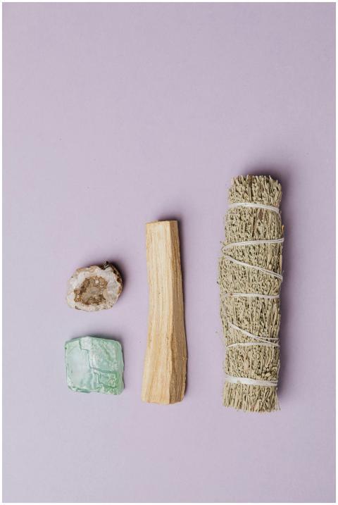 Flat lay of sage, crystal, and wood on a light pur