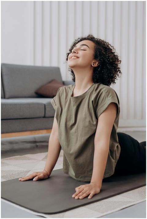 A smiling young woman practicing yoga on a mat ind