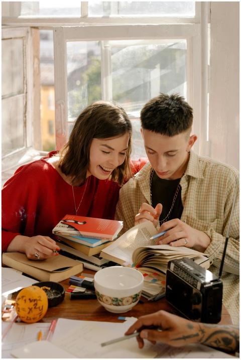 Two young adults study together with textbooks at