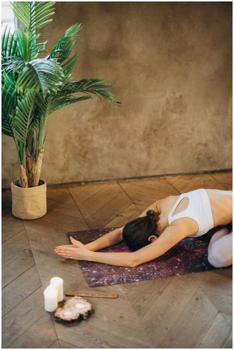 Woman in child's pose on yoga mat with candles and