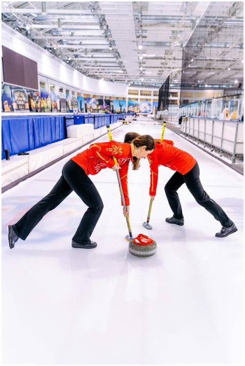 Dynamic shot of women curling players sweeping a s