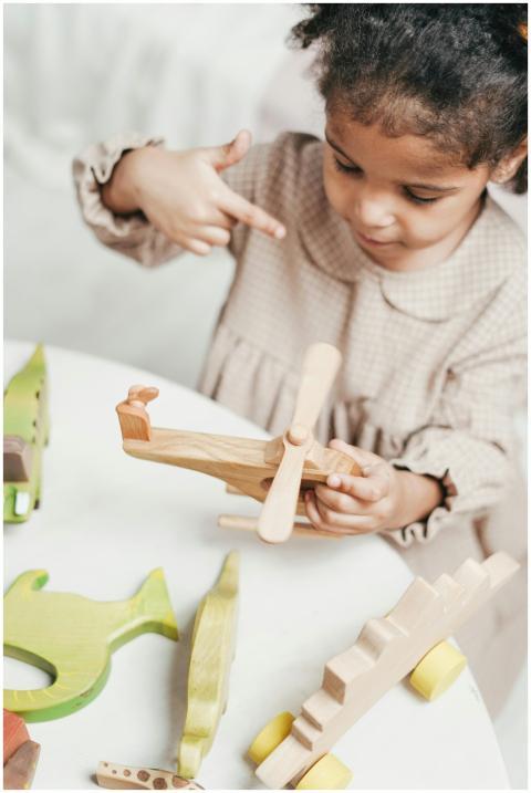 An adorable child plays with a wooden airplane toy
