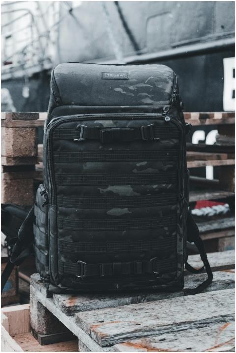 A durable black backpack rests on wooden pallets i