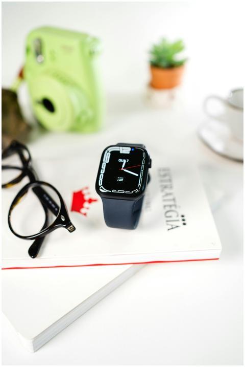 Close-up of a smartwatch and eyeglasses on a book,