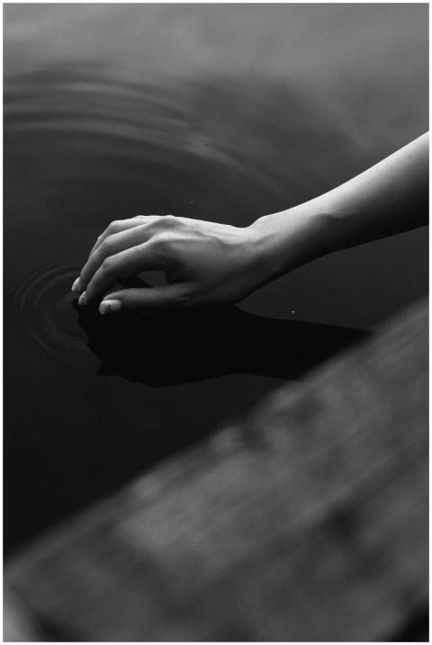 A serene black and white photograph of a hand touc