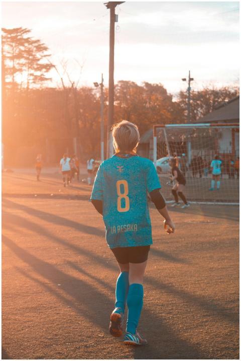 Teen girl in soccer attire on field at sunset, sho