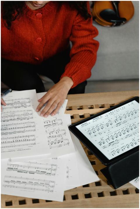 A woman in a red sweater reviews music sheets on p