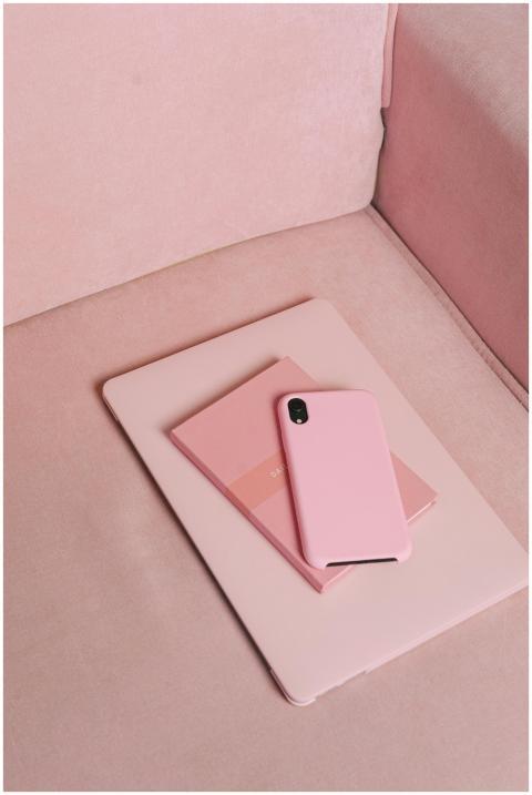 A pink smartphone and matching notebook on a paste