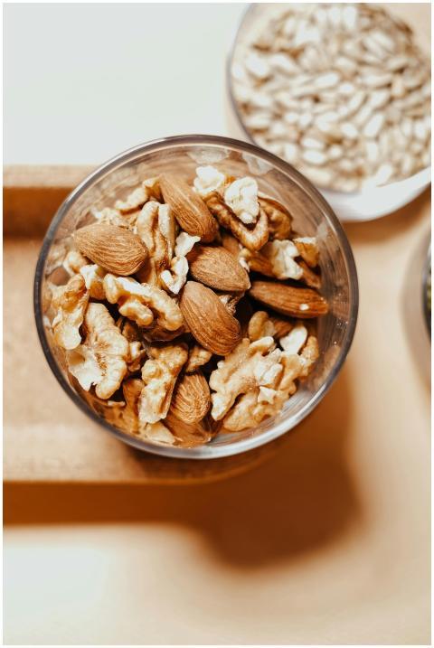 A high-angle shot of almonds and walnuts in a glas