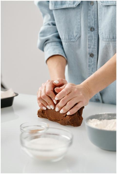 Person kneading chocolate dough with flour and sug