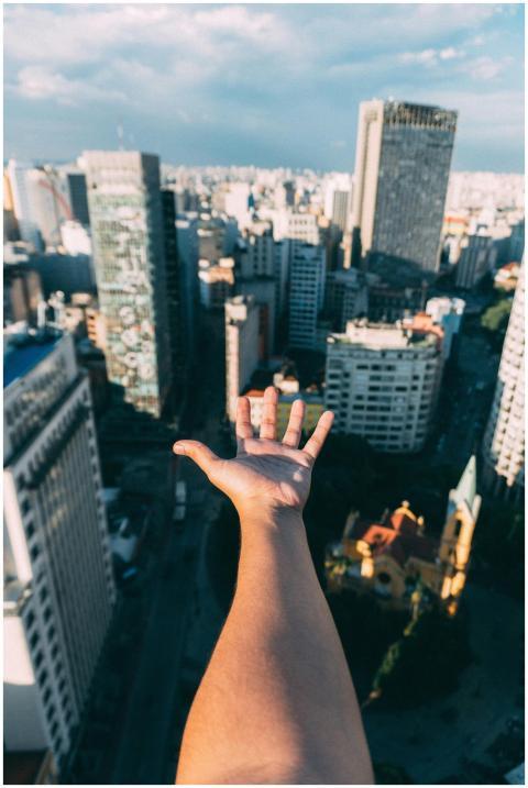 Hand reaching towards a vibrant city skyline on a