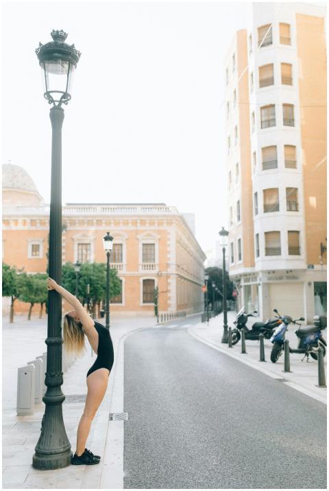 A woman stretching on a city street, leaning again