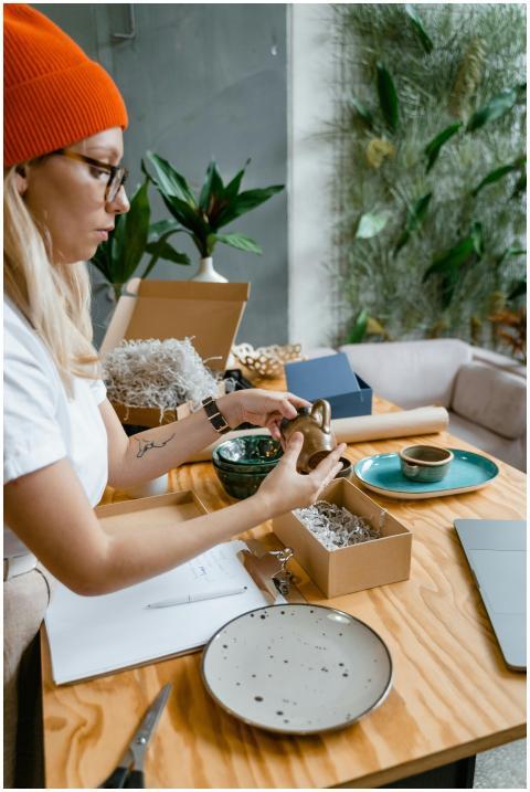 A woman packs ceramic items in a box, preparing th