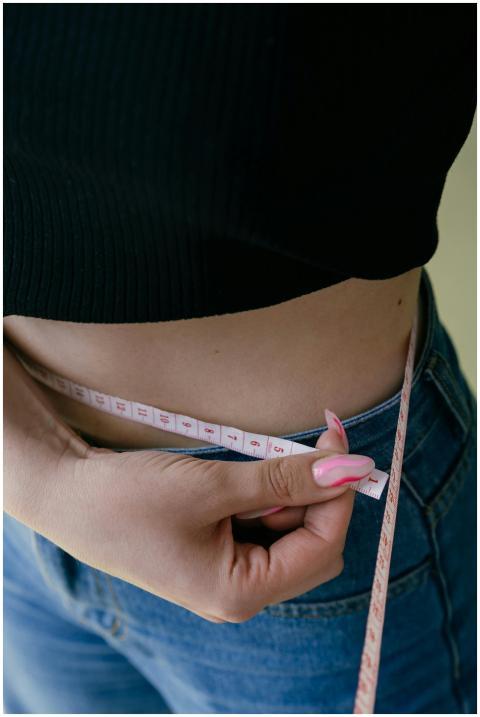 A woman measures her waist with a tape measure, fo