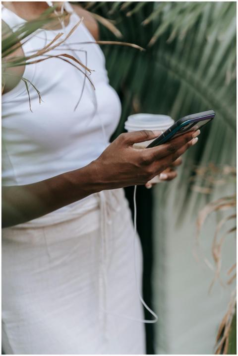 A woman holds a smartphone and a coffee cup surrou