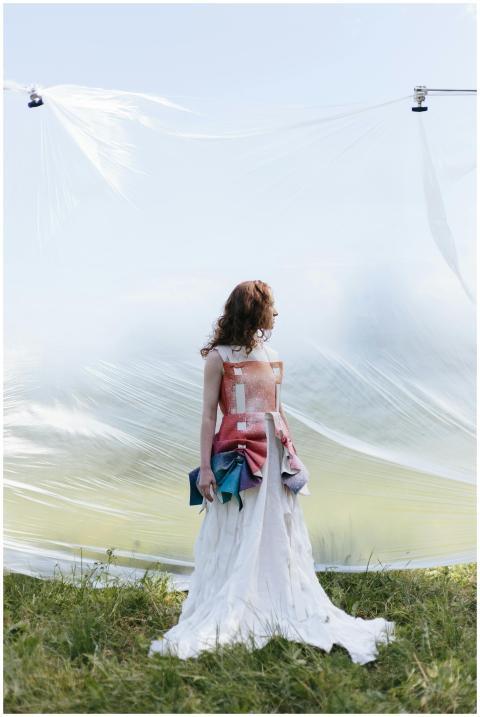 A female model in a conceptual outfit stands outdo