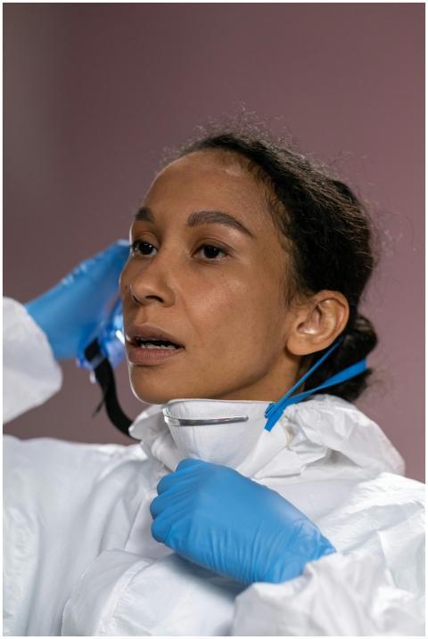 Woman in protective suit and gloves adjusting mask