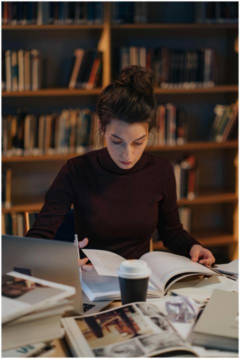 A woman intensely studying books in a library, sur