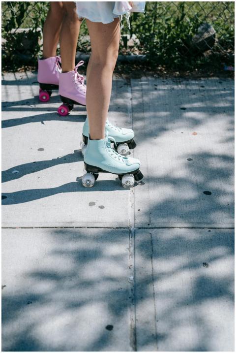 Two women roller skating with pastel boots on a su